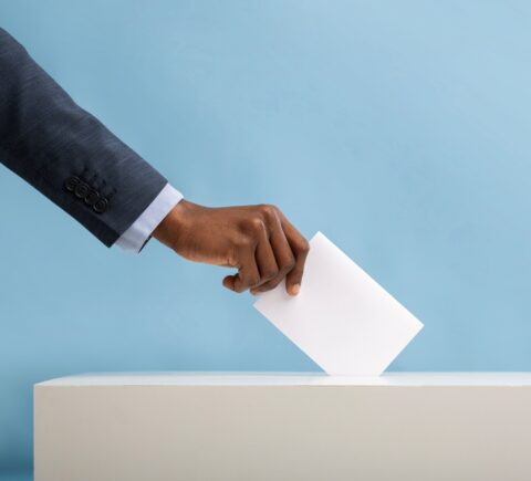 Person wirft Stimmzettel in Wahlurne