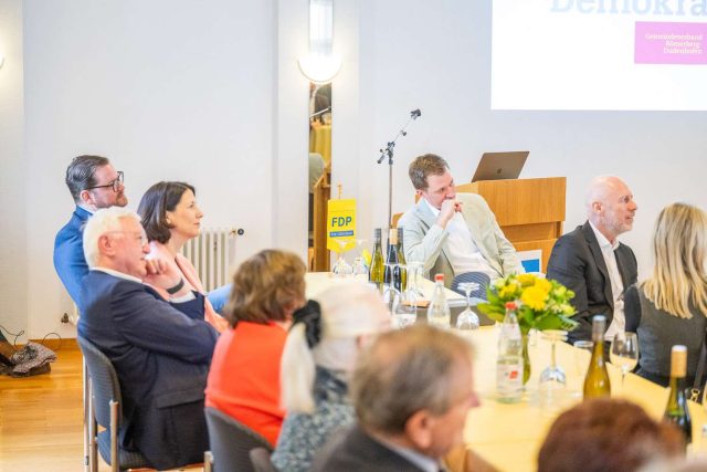 Personen bei einer Konferenz mit FDP-Logo.