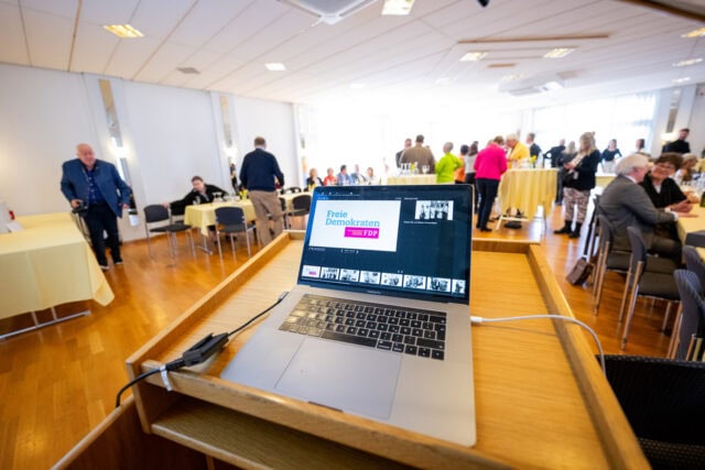 Laptop mit FDP-Logo bei Veranstaltung.